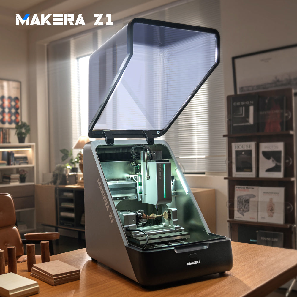 Makera Z1 desktop CNC machine for wood carving in a home workshop, with the cover open and a wooden workpiece mounted on the rotary axis.